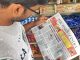 A person in India reading a newspaper about Government of India's notification under the PMLA, regulating virtual digital asset activities for businesses to prevent money laundering.